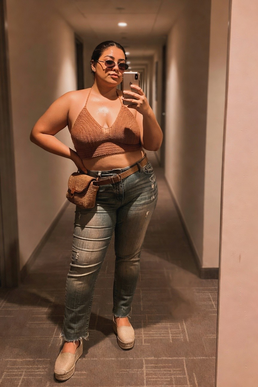 Woman in brown crochet top and ripped jeans taking a mirror selfie.