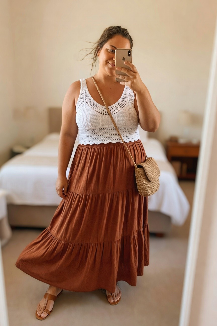 Woman in white crochet top and tiered rust maxi dress taking a mirror selfie.