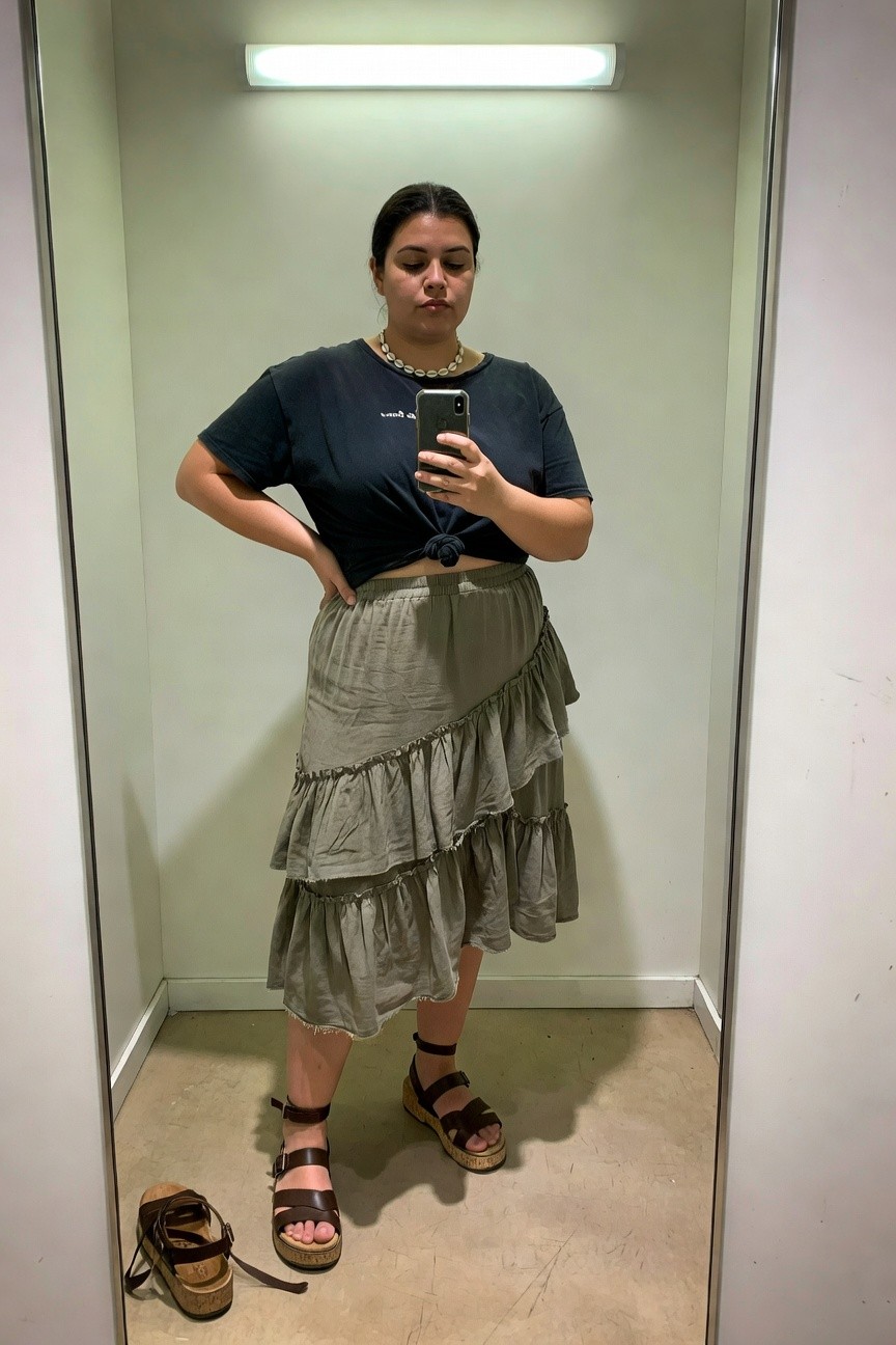 Woman in navy top and tiered sage skirt taking mirror selfie in sandals.