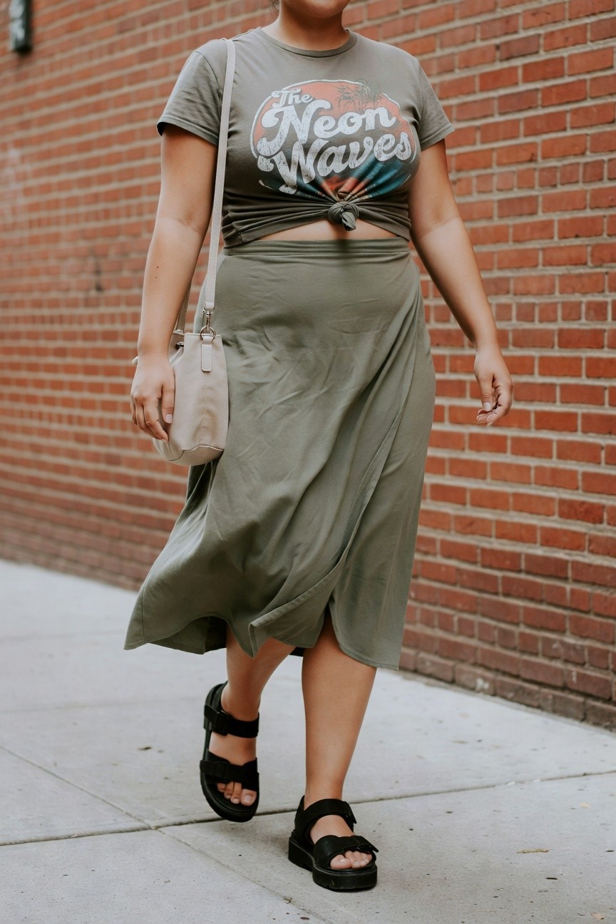 Person wearing olive-green knotted tee and matching midi skirt with black sandals.