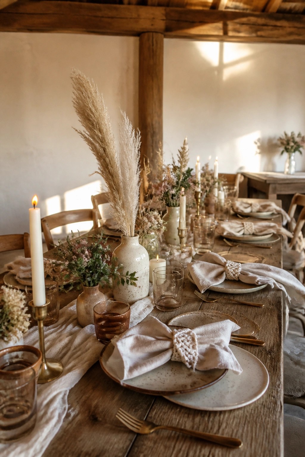 Long wooden wedding table styled with tall pampas grass macrame napkin rings ceramic plates and glowing candles in a rustic boho style