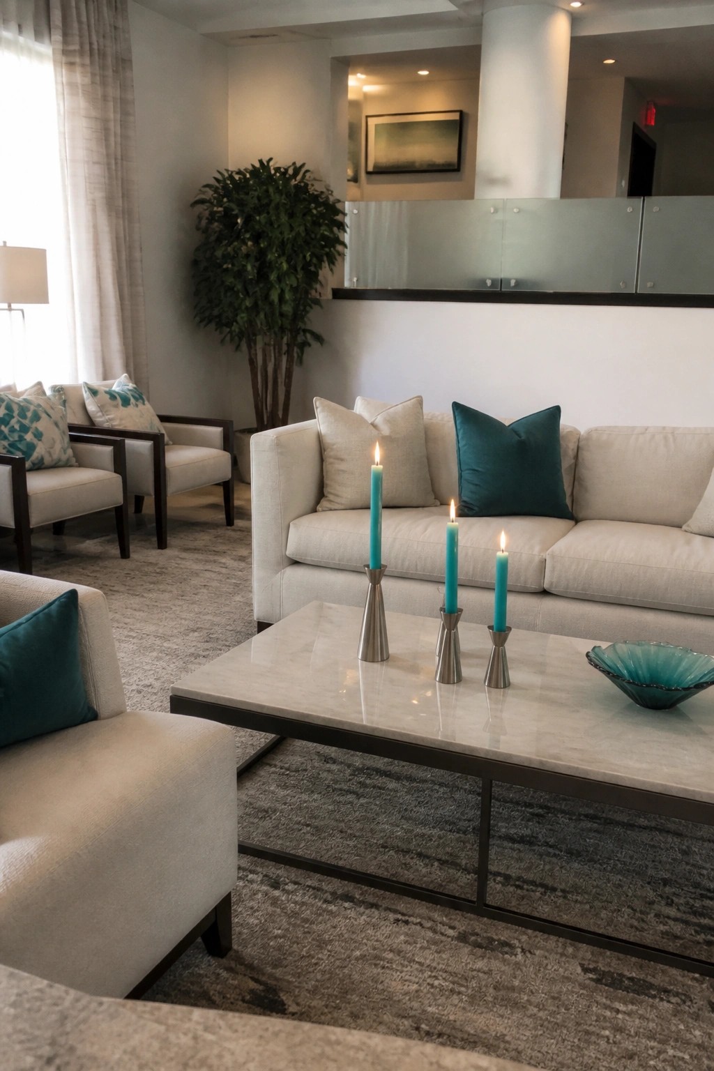 Modern wedding lounge with cream sofas teal pillows and lit candles on a marble table in a bright contemporary space