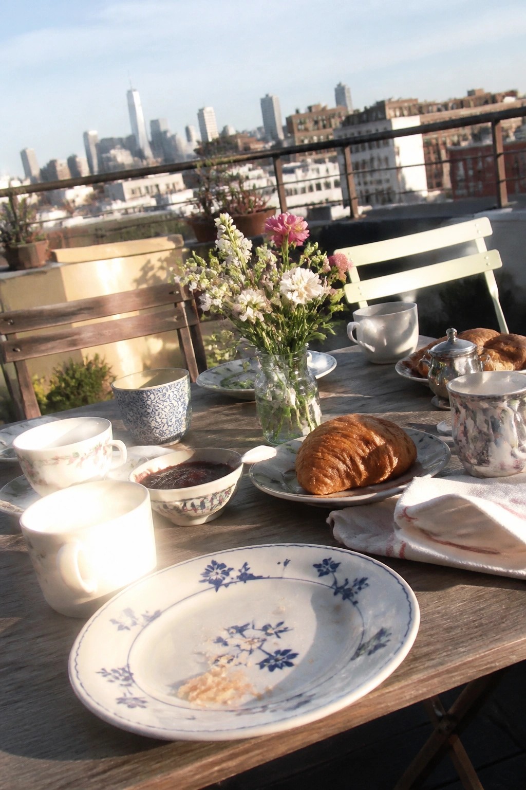 Intimate rooftop wedding breakfast with croissants flowers and city skyline at sunrise