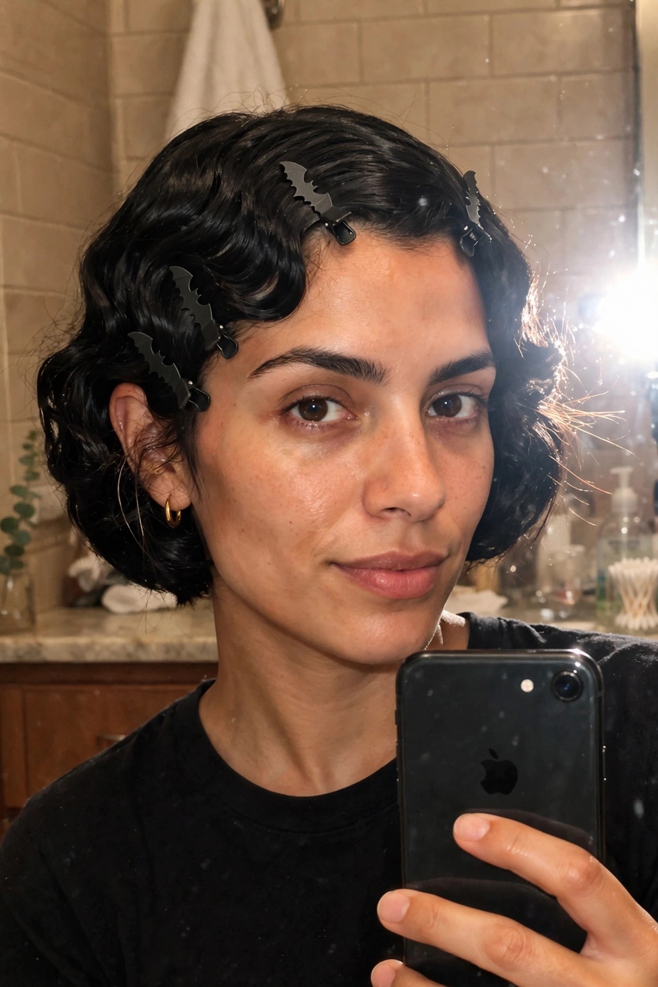 Short curly black bob hairstyle with multiple black bat shaped clips placed throughout the hair.