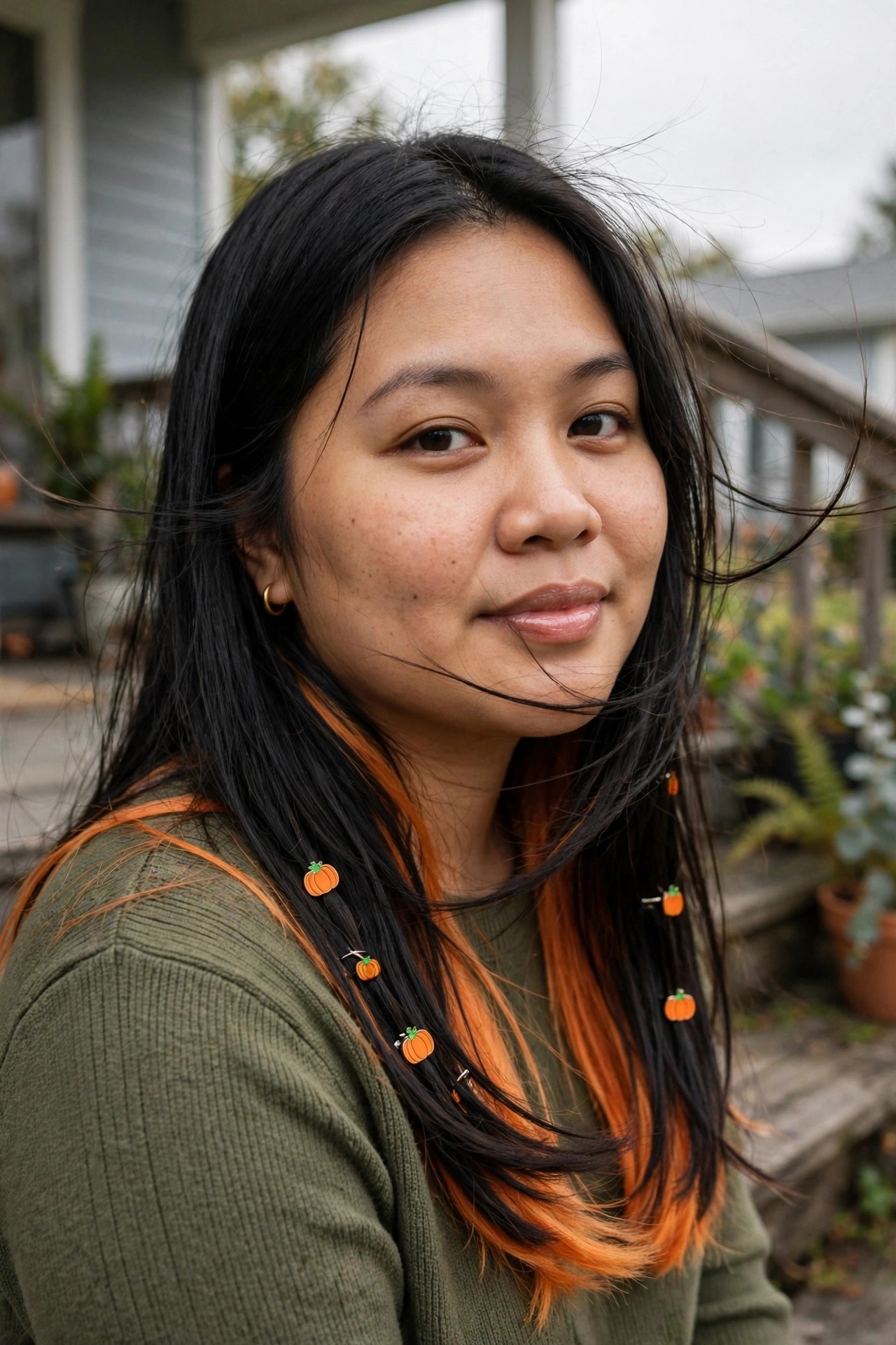 Long black hair with orange streaks and several small orange pumpkin charms clipped along individual strands.