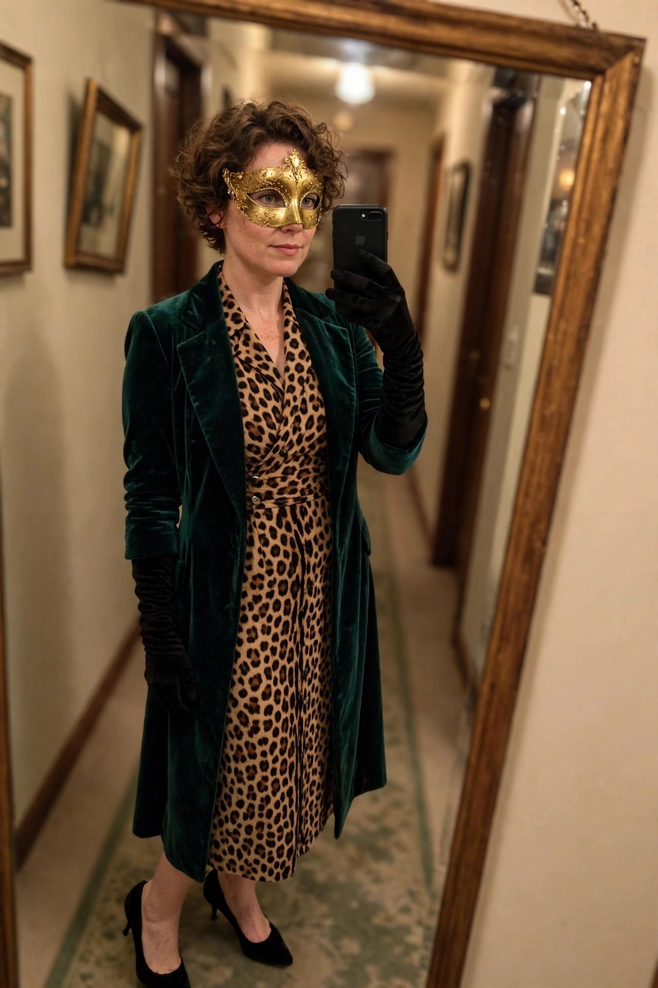 Woman wearing a leopard print dress under a long green velvet coat with a gold masquerade mask and black gloves.
