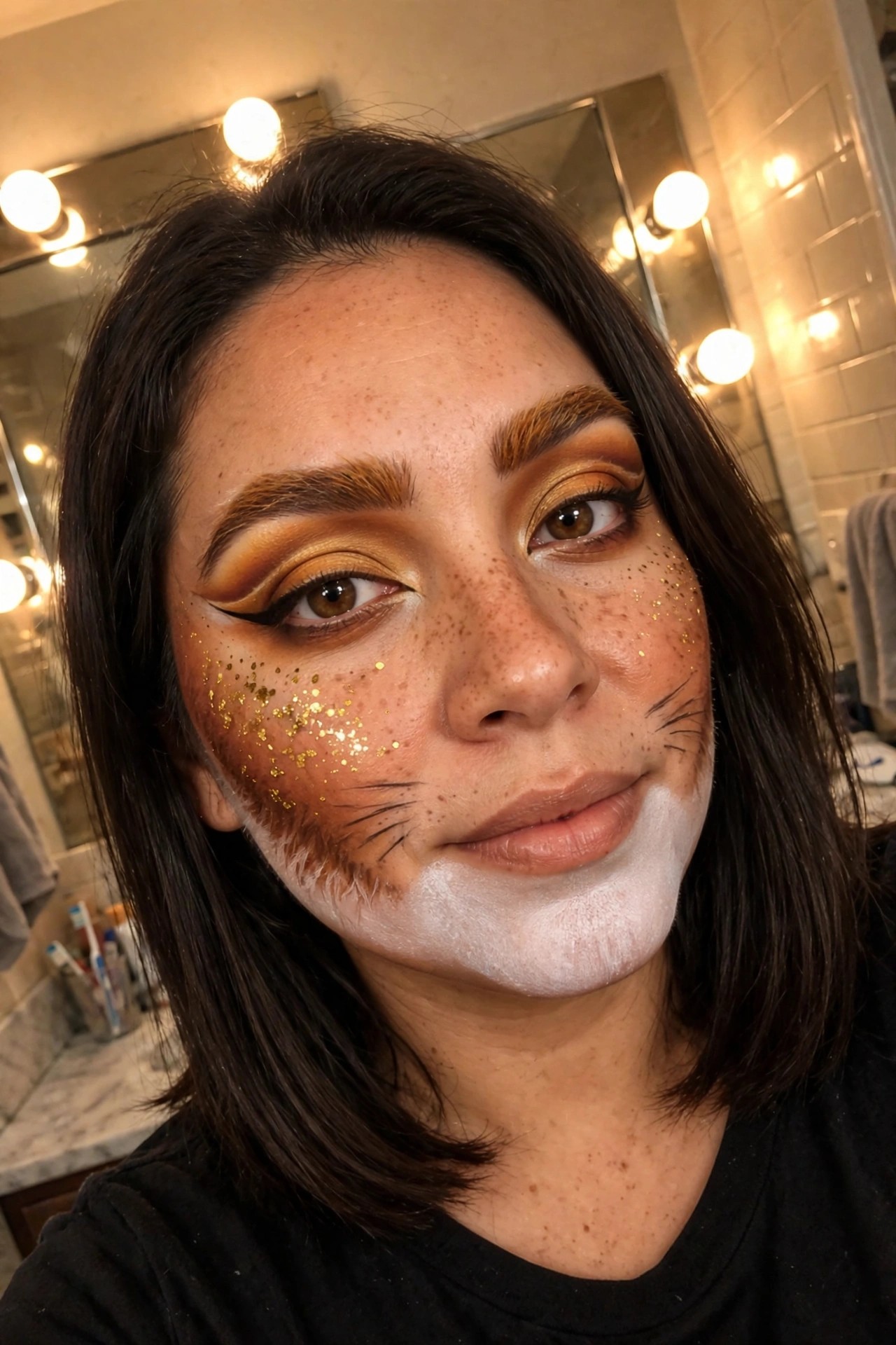 Close-up of cat makeup with gold glitter on cheeks, black whiskers, white lower face paint, and warm gold eyeshadow.