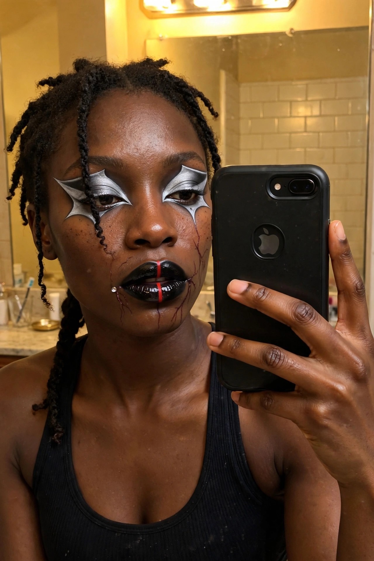Close up of silver metallic bat wing eye makeup with black lips featuring a red center line, red vein details on cheeks, and a small gem accent near the mouth.